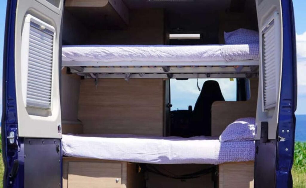 A man working on his laptop and writing in a notebook at a desk.