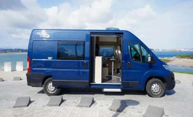 Blue camper van parked with sliding door open, showing interior.
