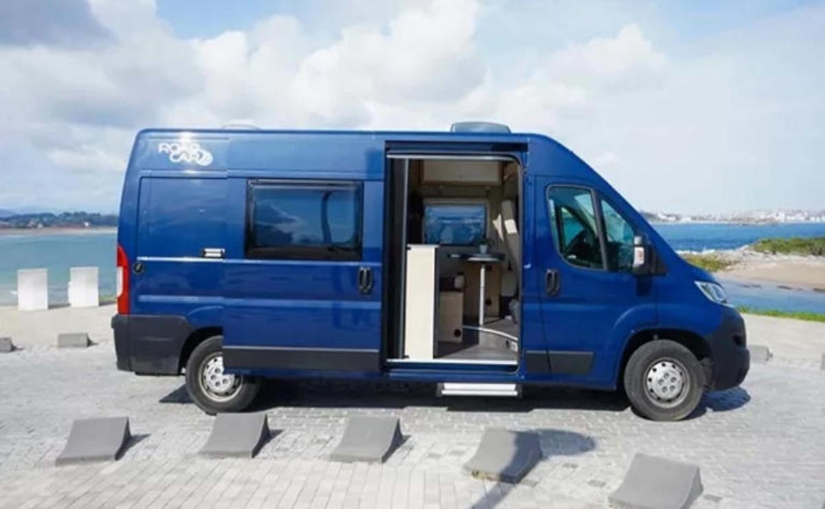 Blue camper van parked with sliding door open, showing interior.