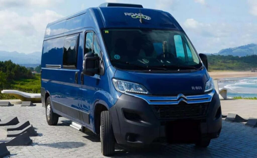 A man working on his laptop and writing in a notebook at a desk.