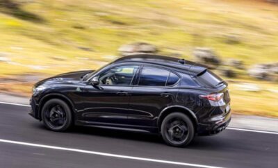 A sleek black SUV driving fast on a road.