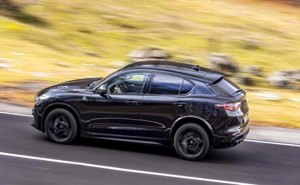 A sleek black SUV driving fast on a road.
