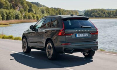 Black Volvo SUV driving on a scenic road near water.