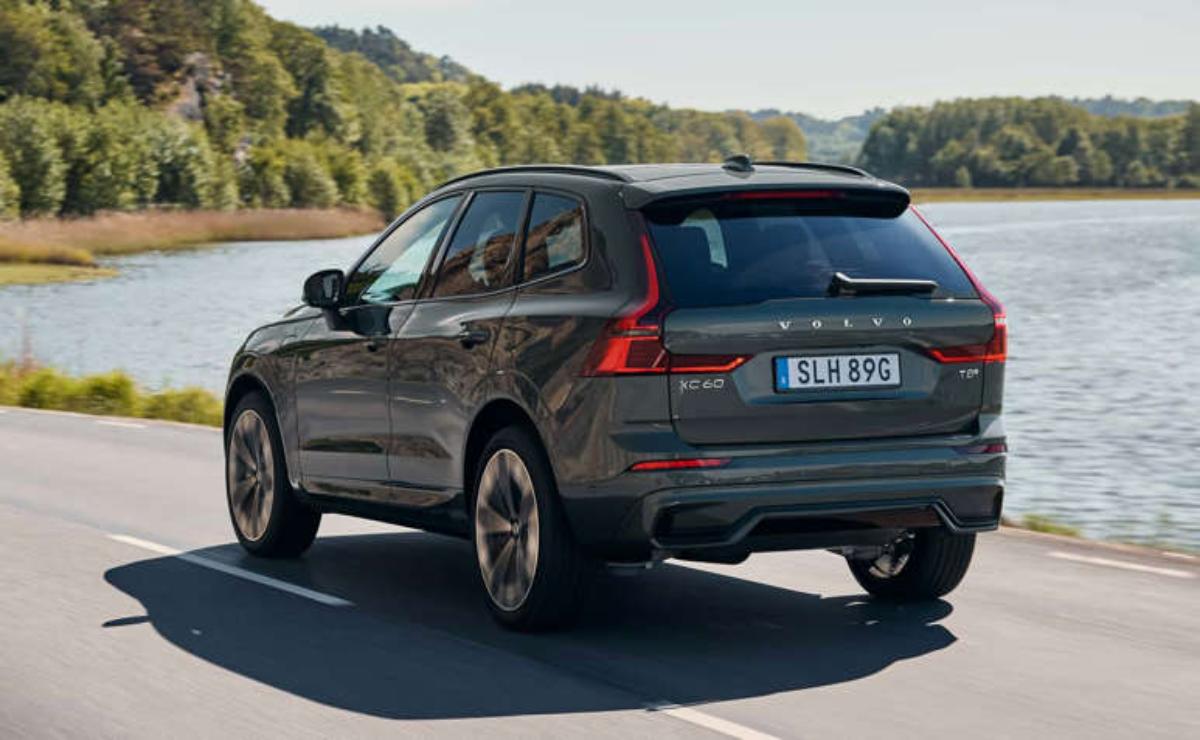 Black Volvo SUV driving on a scenic road near water.