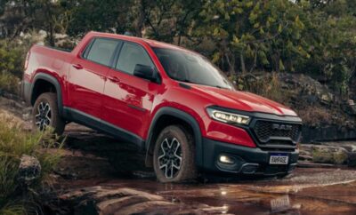 Red SUV parked on rocky terrain near a forest.