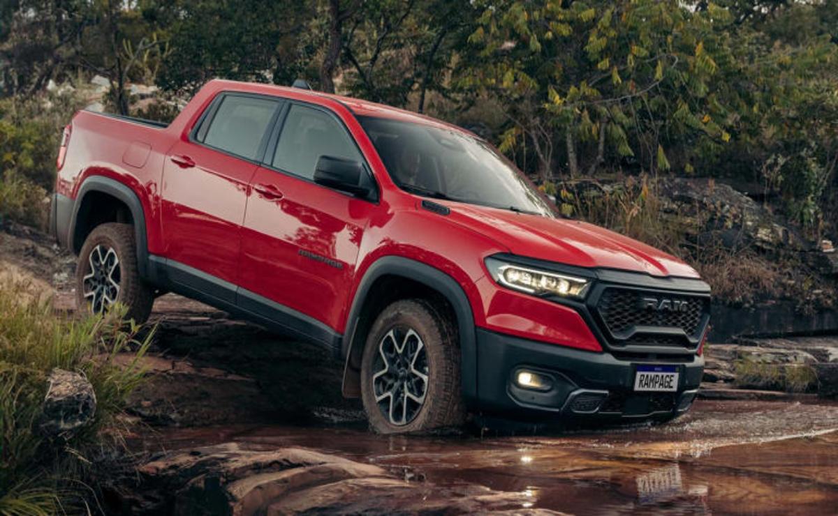 Red SUV parked on rocky terrain near a forest.
