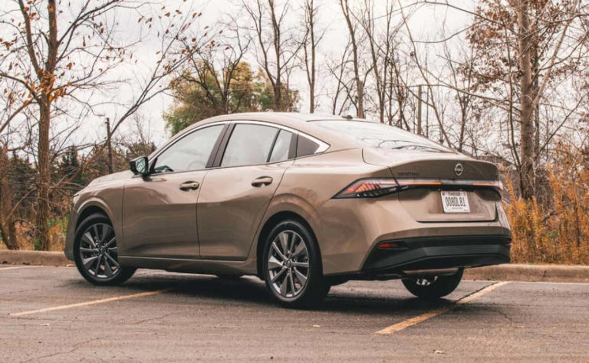A sleek beige sedan parked on an empty street with trees in the background.