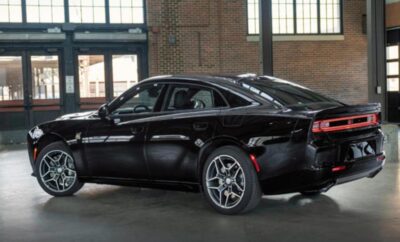 Black Dodge Charger parked indoors with large windows in the background.
