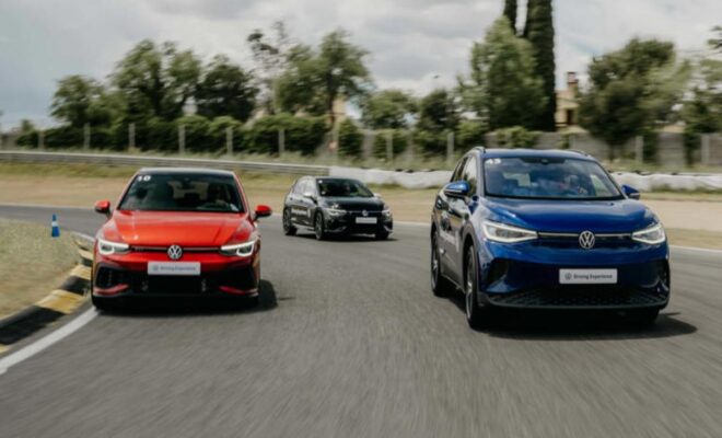 Three cars driving on a road, with a red, black, and blue car.