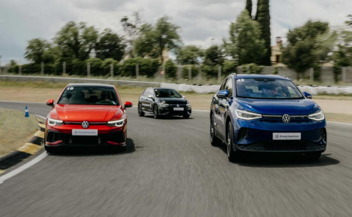 Three cars driving on a road, with a red, black, and blue car.
