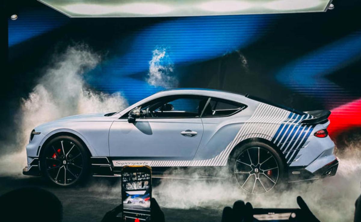 A sleek silver sports car with custom blue and black stripes, surrounded by smoke effects.