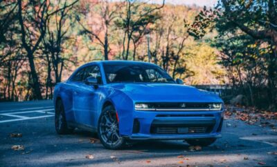A blue Dodge Challenger SRT parked outdoors with autumn trees in the background.