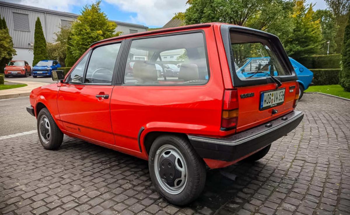 Classic red compact car parked on a cobblestone street.