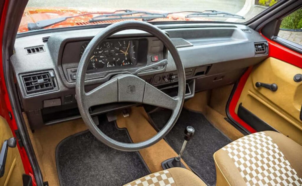 A man working on his laptop and writing in a notebook at a desk.