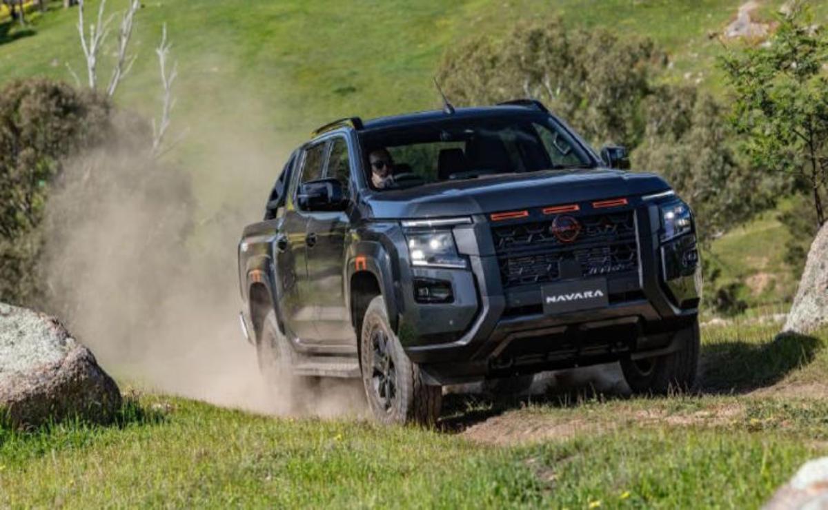 A black GMC truck driving off-road on a grassy terrain.
