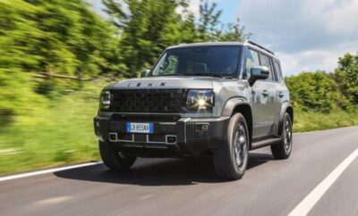 A black off-road SUV driving on a road with greenery in the background.