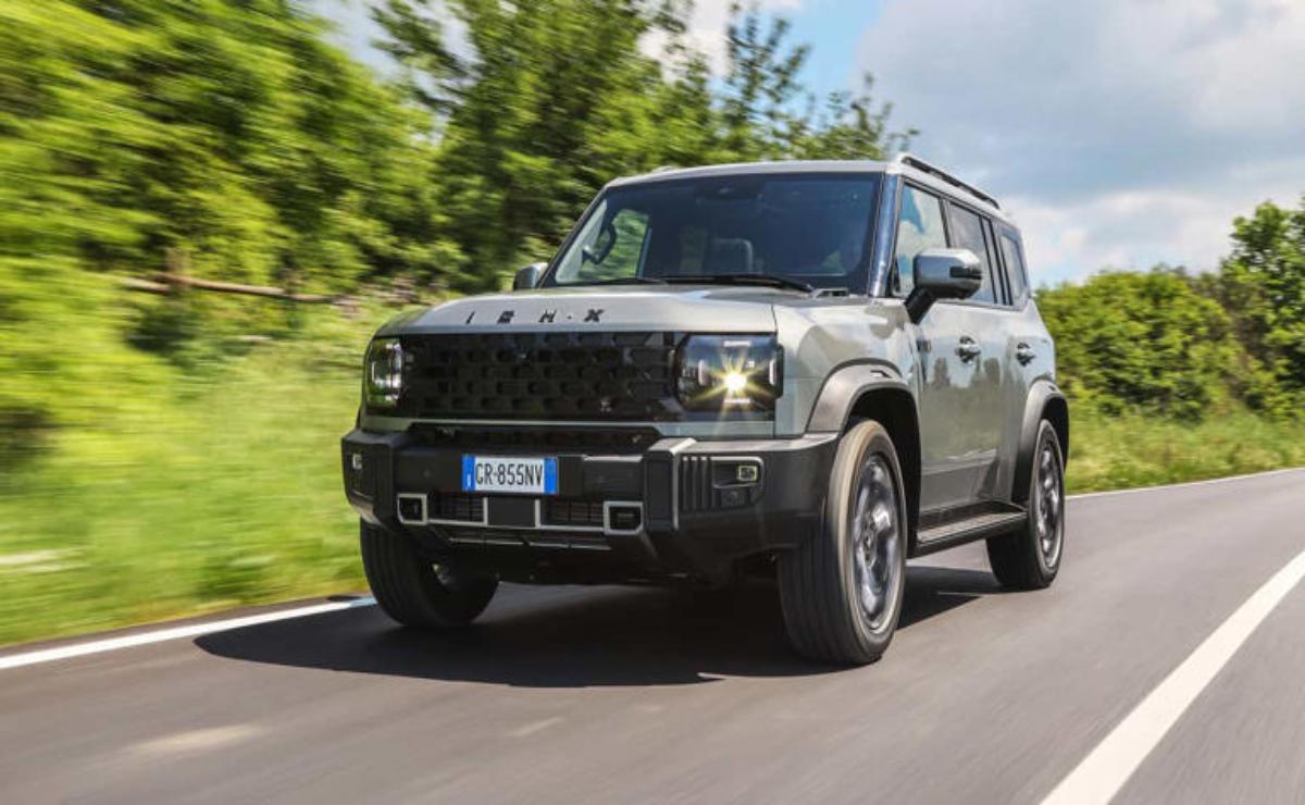 A black off-road SUV driving on a road with greenery in the background.