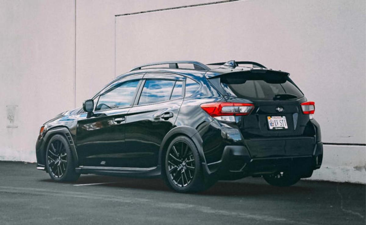 Black sporty hatchback car parked beside a wall.