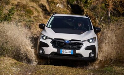 A white SUV driving on a rugged dirt road in a natural setting.