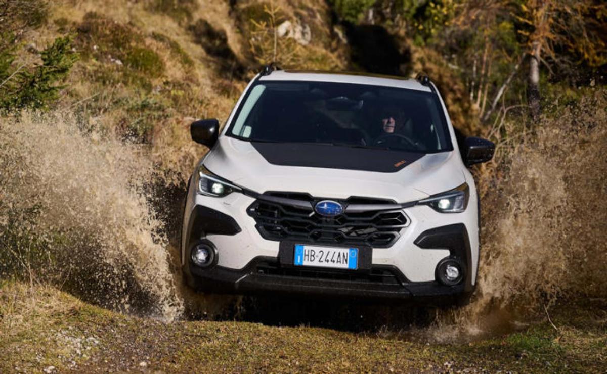A white SUV driving on a rugged dirt road in a natural setting.