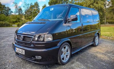 Black van parked outdoors with shiny rims and clear headlights.