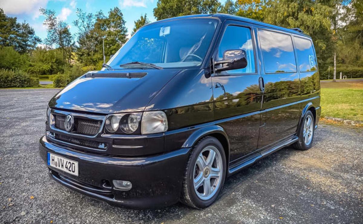 Black van parked outdoors with shiny rims and clear headlights.