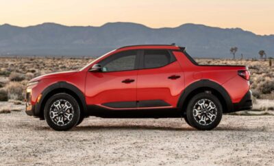 Compact red pickup truck parked in a desert landscape at sunset.