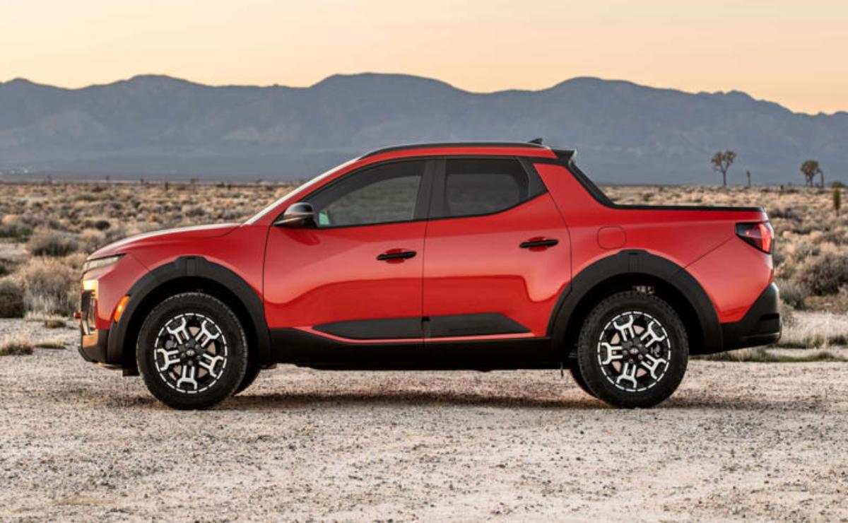 Compact red pickup truck parked in a desert landscape at sunset.