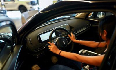 Person holding steering wheel inside a modern car.