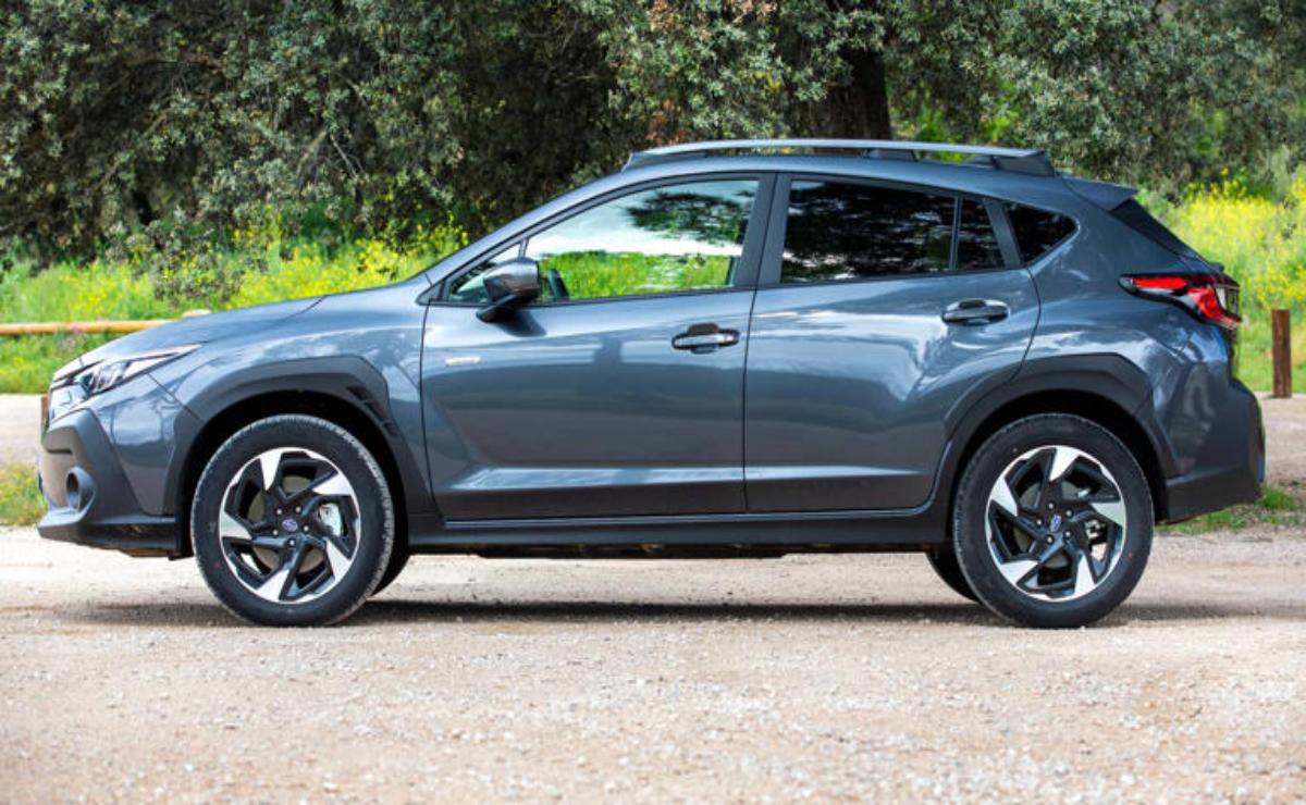 A modern gray SUV parked on a dirt road with greenery in the background.