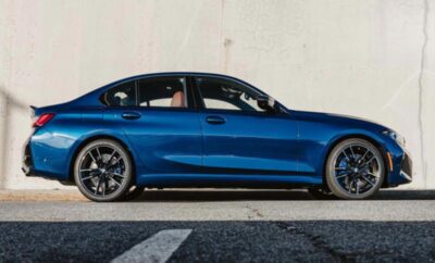 A sleek blue sports sedan parked by a white wall.