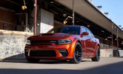 Red Dodge Charger parked under a building with black wheels.