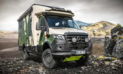 A rugged off-road camper van in a mountainous terrain under a cloudy sky.
