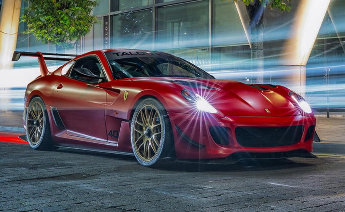A sleek red sports car with glowing headlights on a city street at night.