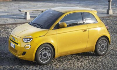 A sleek yellow compact car parked on a cobblestone street.