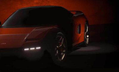 Sleek red sports car illuminated in low light, showcasing its modern design.