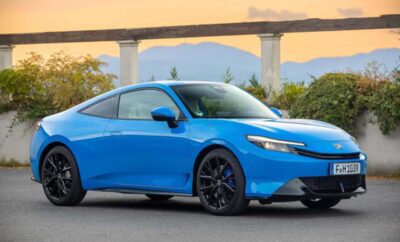 Sleek blue sports car parked with modern bridge backdrop.
