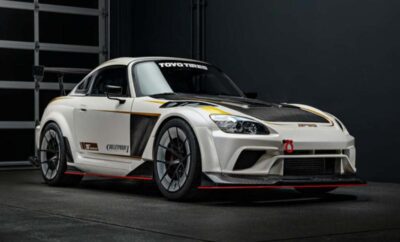 Sleek white sports car with aerodynamic design and racing decals in a dark studio.