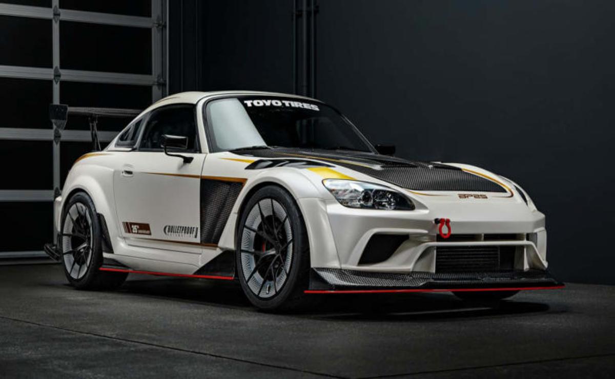 Sleek white sports car with aerodynamic design and racing decals in a dark studio.