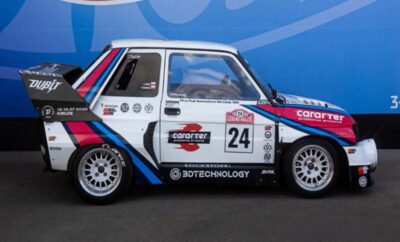 A vintage white racing car with blue and red stripes and number 24 on the door.
