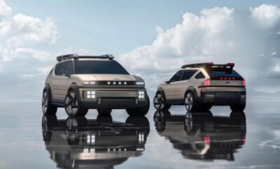 Two futuristic electric SUVs parked on a reflective surface under a cloudy sky.