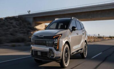 A sleek black SUV driving under a bridge in an urban setting.