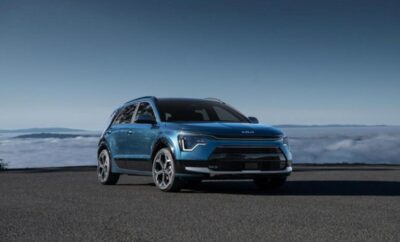 A sleek blue electric SUV parked on an open road under a clear sky.