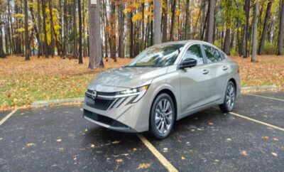 Silver sedan parked on a wet road with autumn trees in the background.