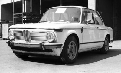 Vintage white BMW car parked outdoors in black and white photo.