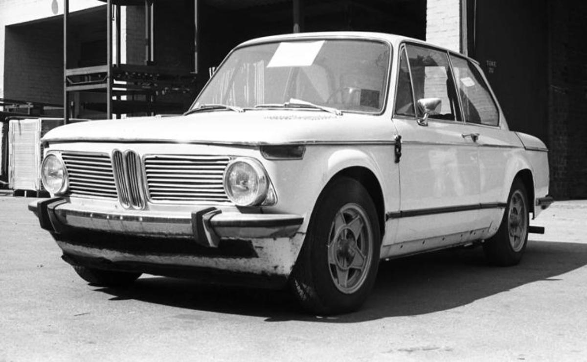 Vintage white BMW car parked outdoors in black and white photo.