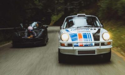 Two vintage race cars speeding on a forest road.