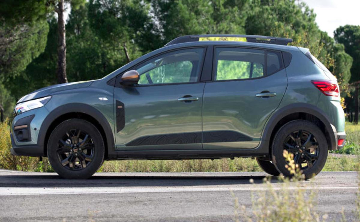 Side view of a green SUV parked on a road with trees in the background.