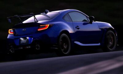 Blue sports car driving on a road at dusk.