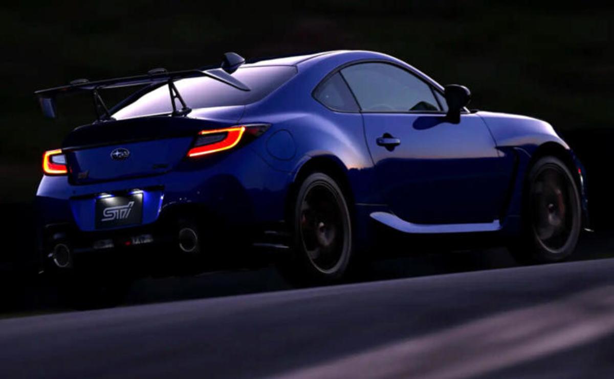 Blue sports car driving on a road at dusk.